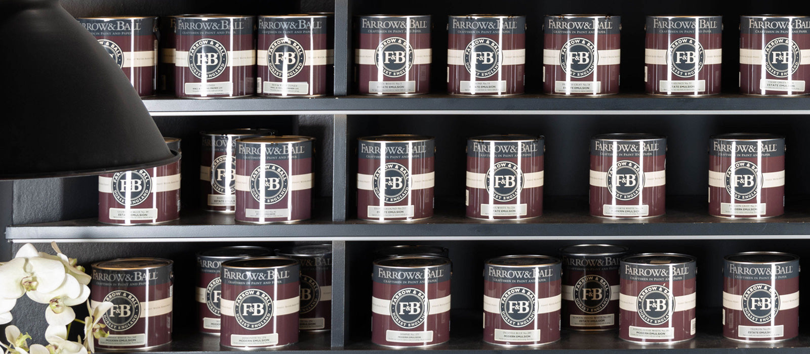 Foto von einem dunklen Regal mit mehreren Farbdosen von Farrow and Ball