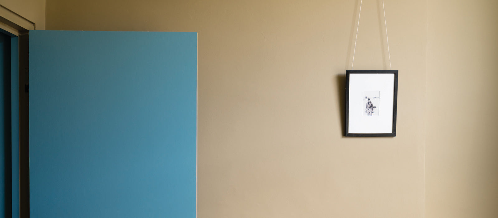 Eine im beige Ton gestrichene Wand und eine in blau lackierte Tür dazu