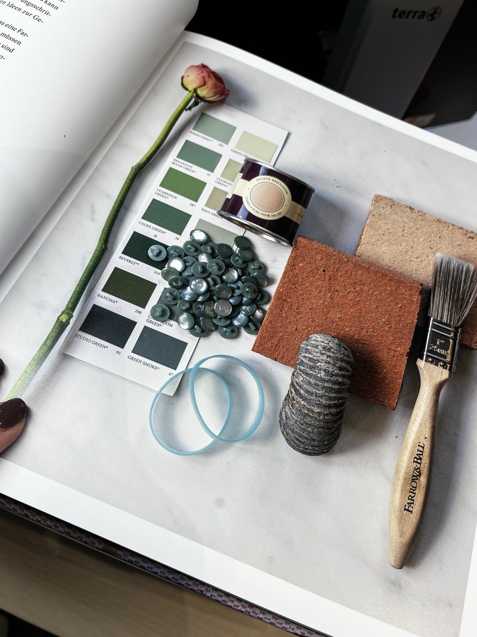 Eine Seite des Buches "Glücklich wohnen mit Farbe" mit Materialien die farblich zu den Farrow & Ball Farbmustern passen