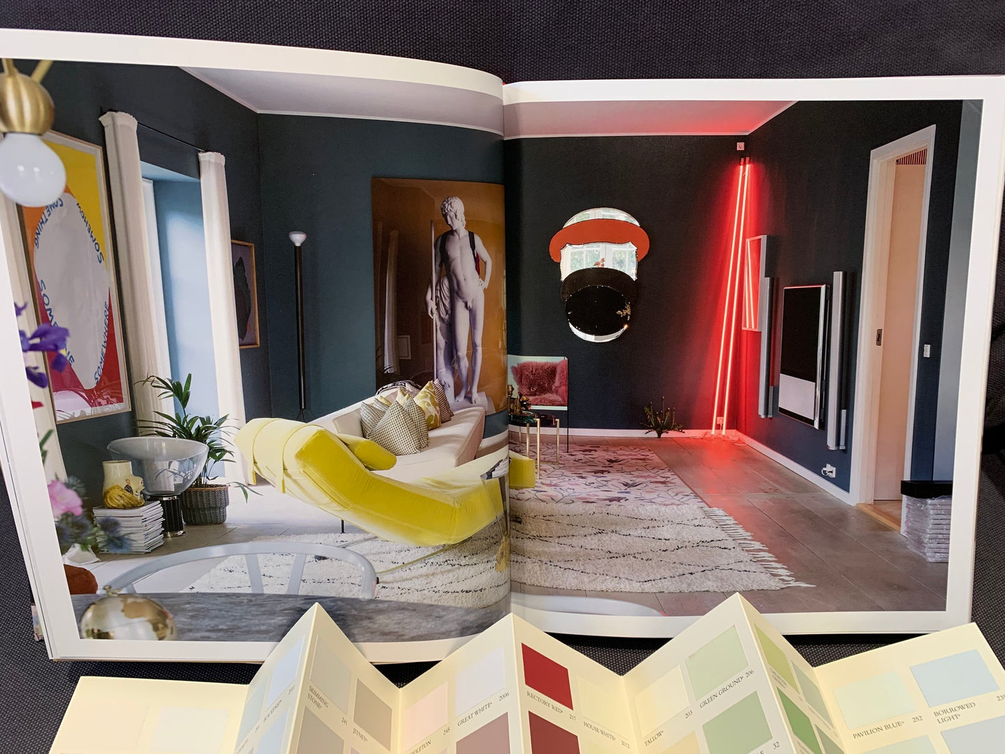 Gestaltungsidee eine modern, fast schon futuristisch eingerichtetem Raums aus dem Buch "Glücklich wohnen mit Farbe". Davor eine offene Farbkarte.