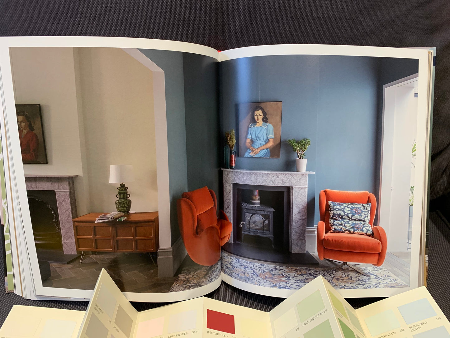Eine Einrichtungskombination mit blau, weiß und orange Tönen aus dem Buch "Glücklich wohnen mit Farbe". Davor eine offene Farbkarte.