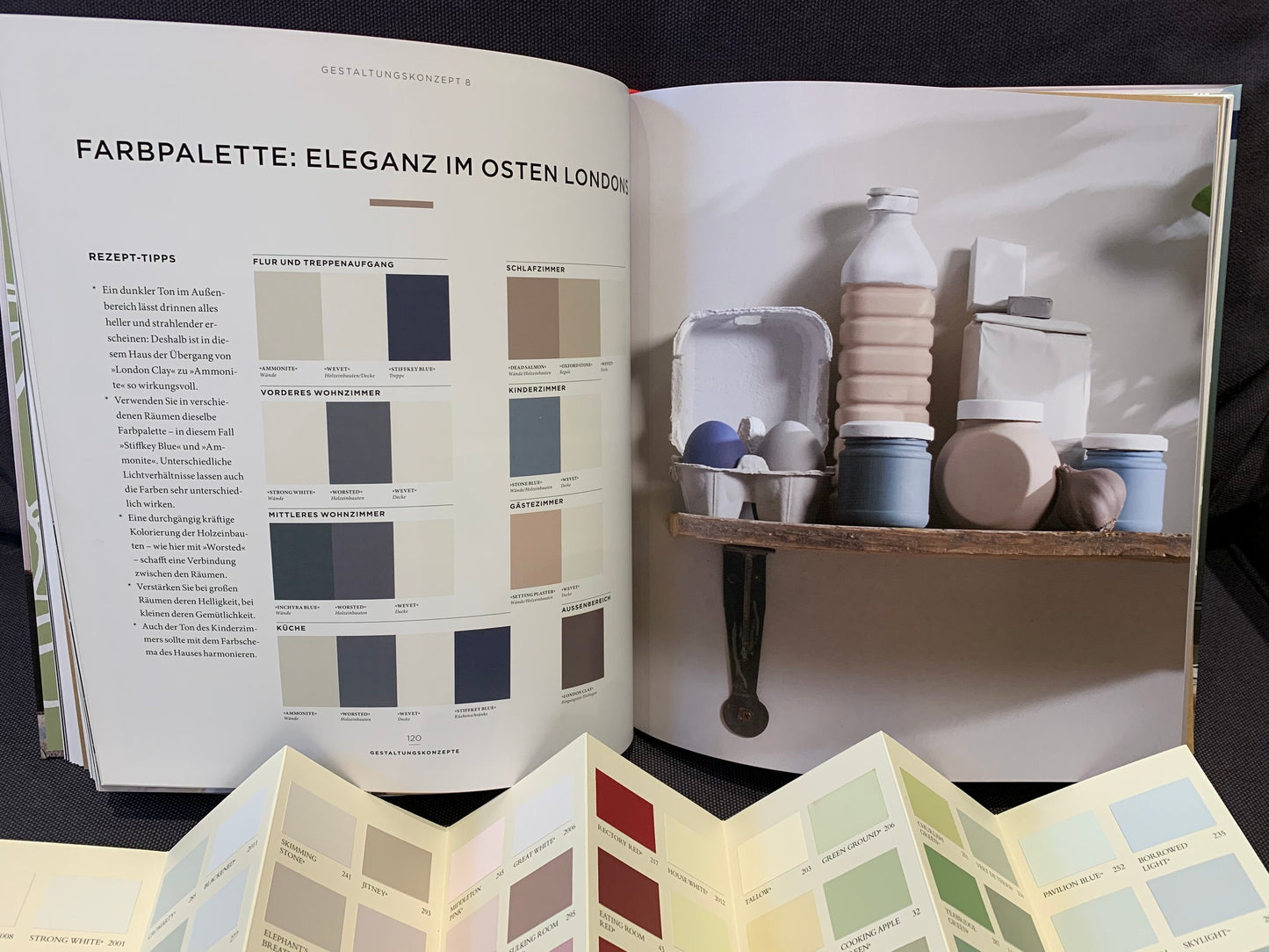 Eine Farbauswahl mit Bildbeispielen aus der Farbpalette von Farrow and Ball zum Thema Eleganz im Osten Londons aus dem Buch "Glücklich wohnen mit Farbe". Davor eine offene Farbkarte.