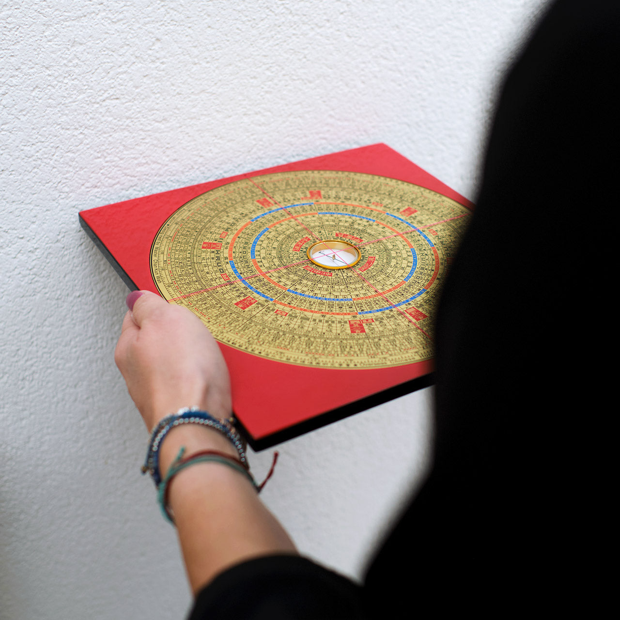 Ein Feng-Shui Board in der Hand einer Frau an einer Hauswand
